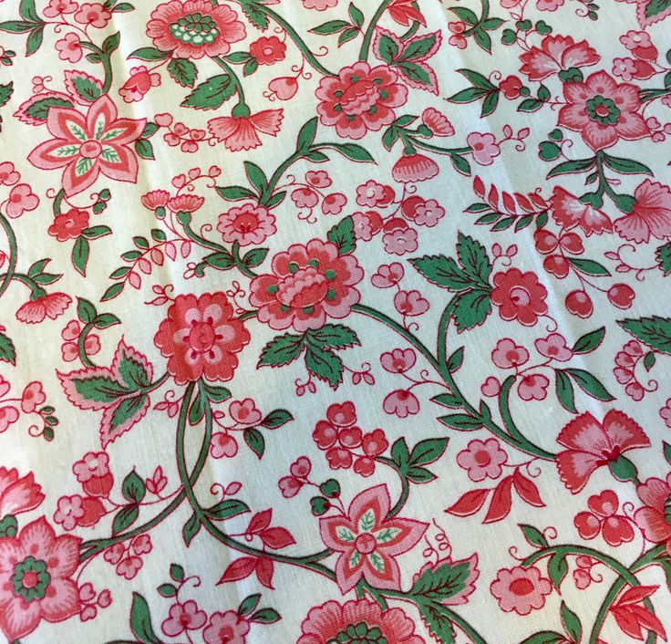 a red and green floral print on white fabric