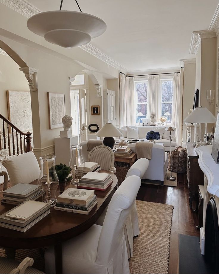 a living room filled with white furniture and lots of books on top of a wooden table