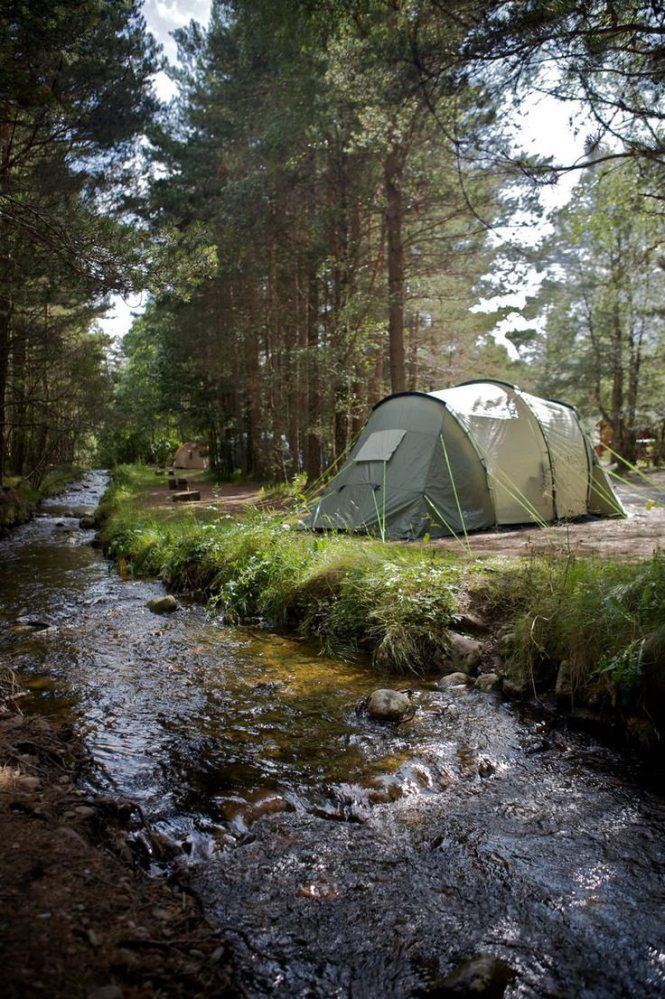 a tent pitched up next to a stream in the woods