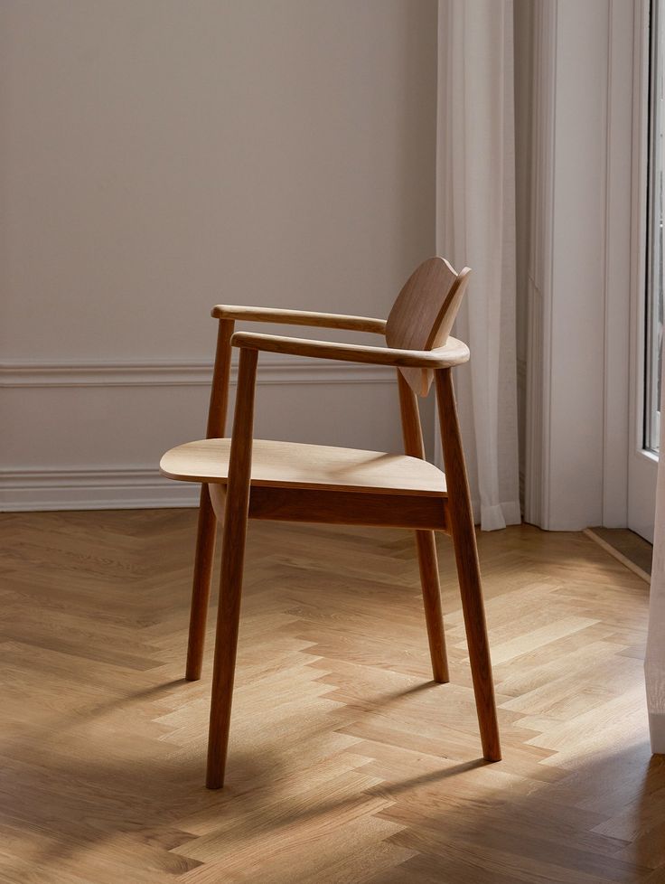 a wooden chair sitting on top of a hard wood floor next to a white wall