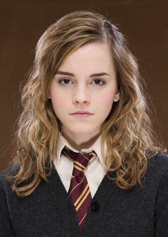 a young woman with long hair wearing a harry potter tie and sweater, looking at the camera