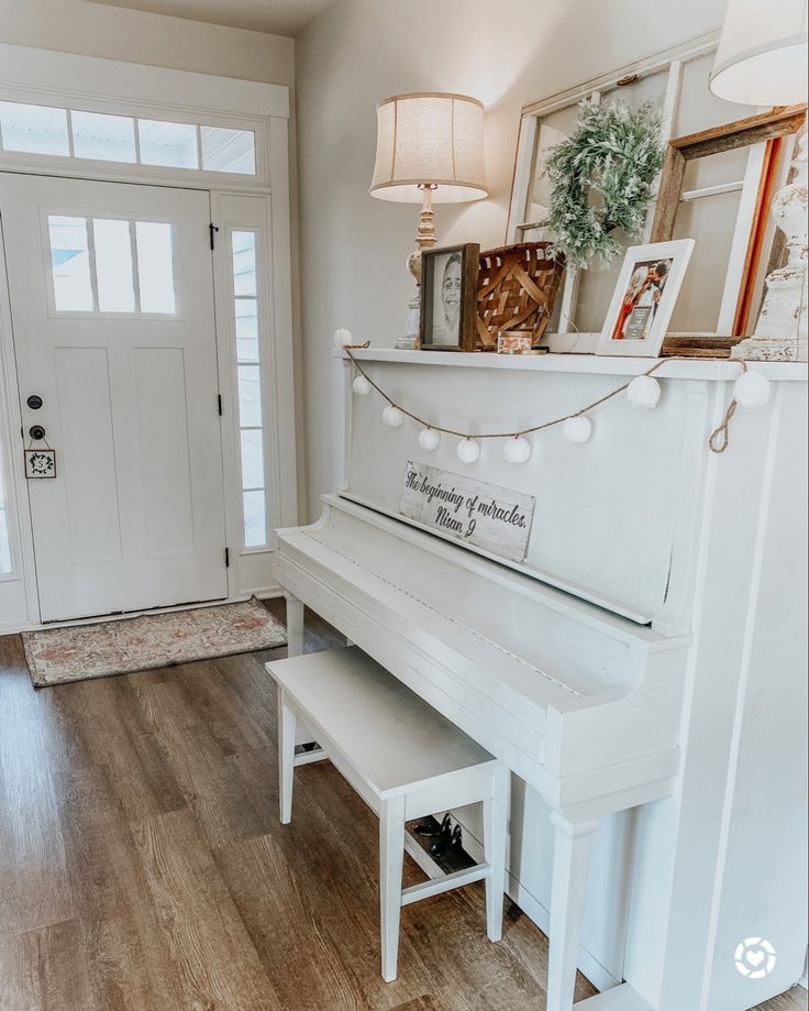 a white piano sitting on top of a hard wood floor in front of a door