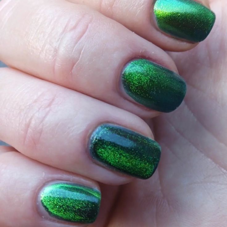 a woman's hand with green and black nail polish