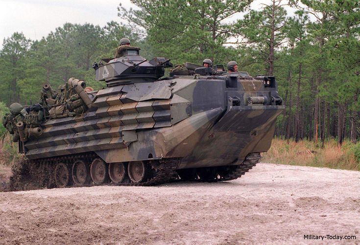 an army tank driving down a dirt road