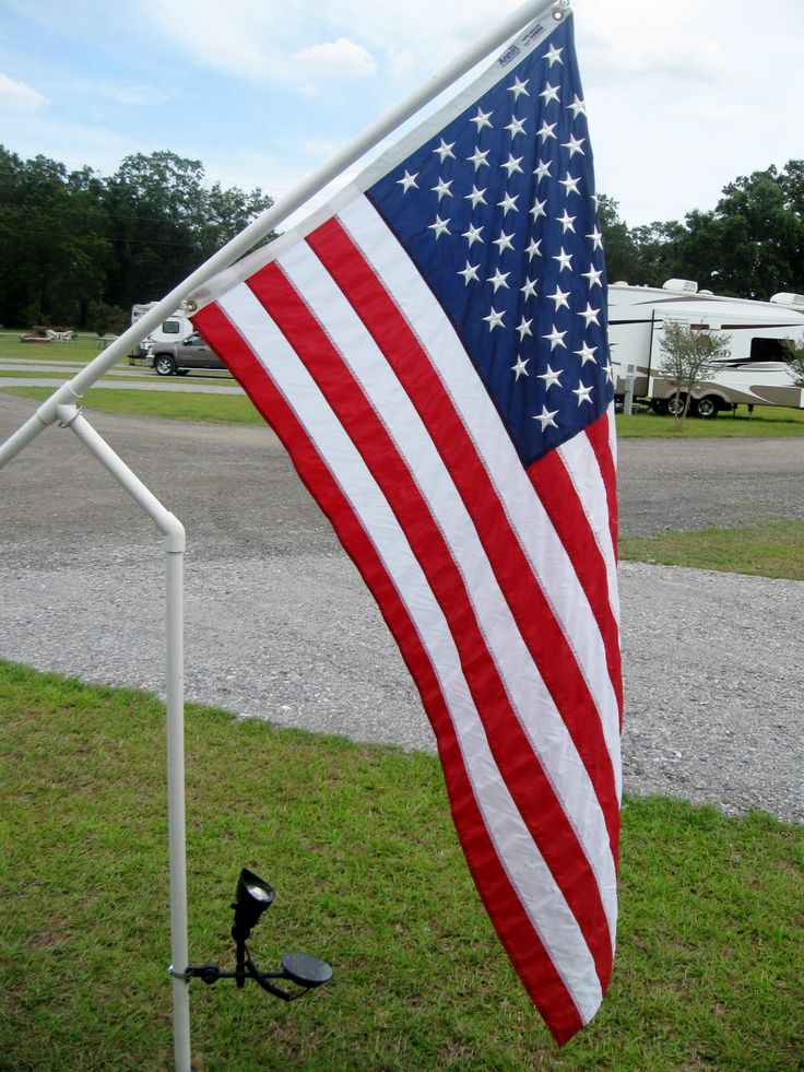 an american flag is in the grass next to a camper trailer and rv park