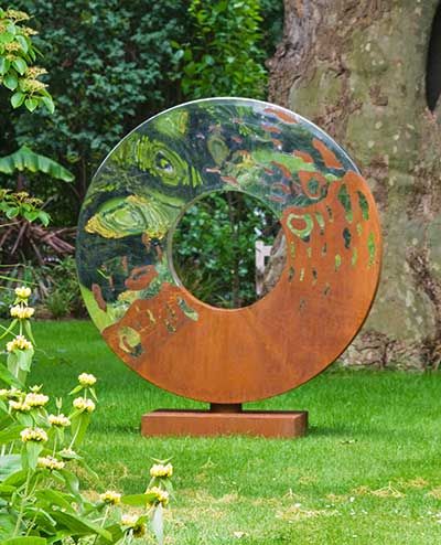 a large metal object sitting on top of a lush green field next to a tree