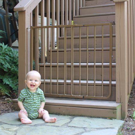 a baby sitting on the ground in front of a stair railing and door to a house