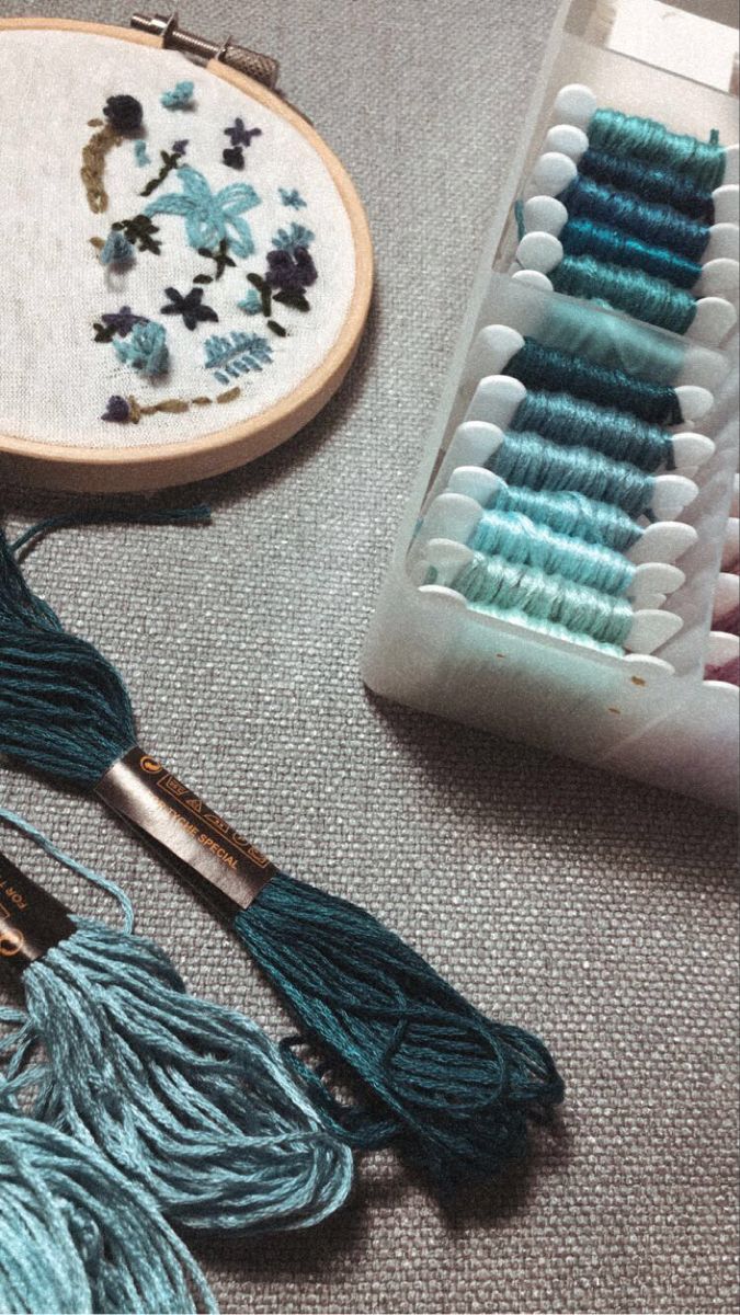 several different types of thread and needles on a table next to an embroidery kit with scissors