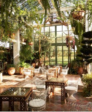 an outdoor dining area with tables and chairs in the middle of it, surrounded by greenery