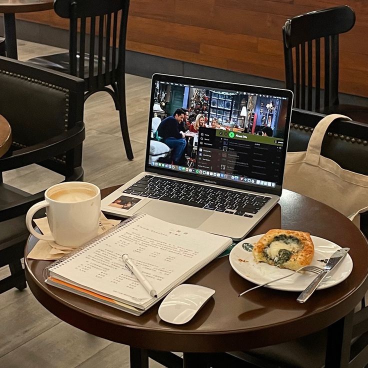 a laptop computer sitting on top of a wooden table next to a cup of coffee