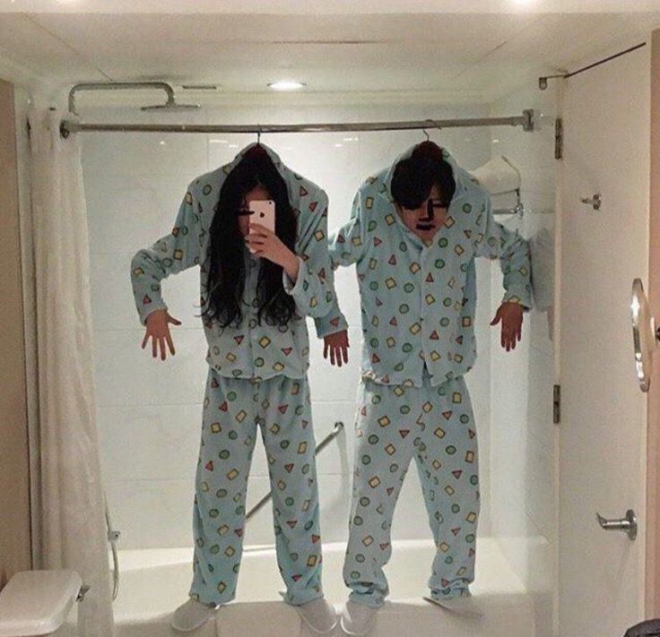 two people in matching pajamas are taking a selfie with their cell phones while standing in the bathroom