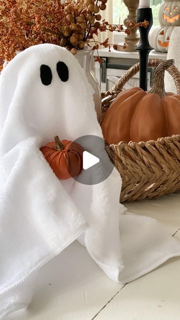 a towel shaped like a ghost with pumpkins in the basket next to it on a table