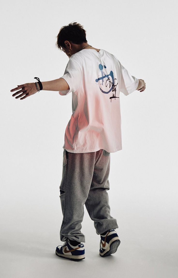 a man standing on top of a skateboard in front of a white wall with his hands out