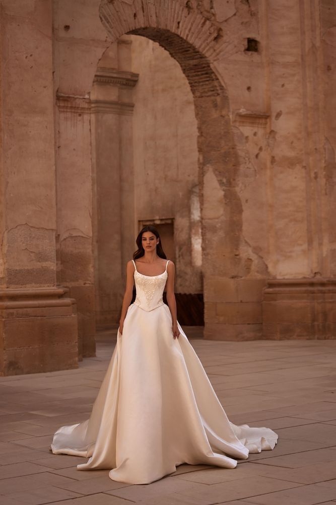 a woman in a white wedding dress standing on a stone floor next to an archway