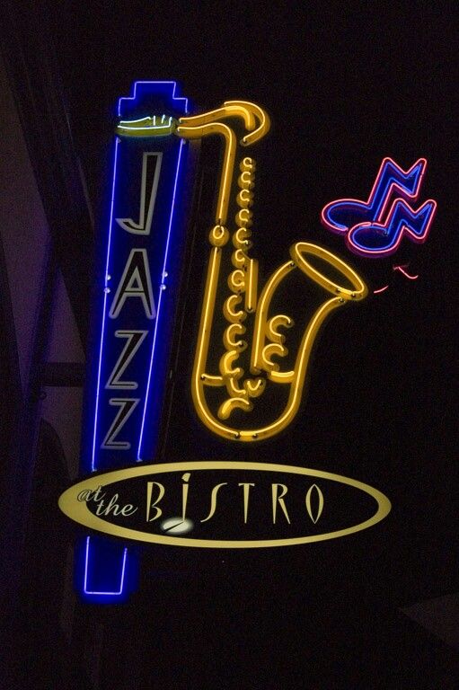 the bistro sign is lit up in blue and yellow neon lights, along with other signs