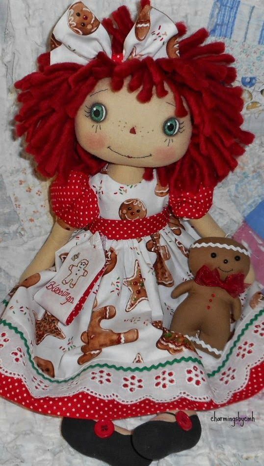 a doll with red hair and green eyes sitting on a white blanket next to a teddy bear