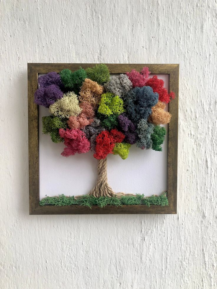 a tree made out of yarn sitting on top of a white wall next to a wooden frame