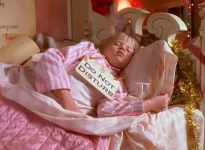 a woman laying in bed with a sign on her stomach that says i do not know what she is