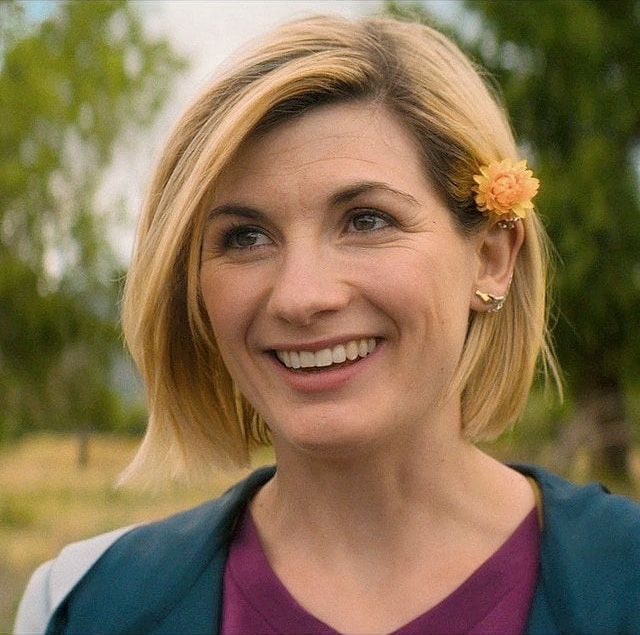 a smiling woman with a flower in her hair