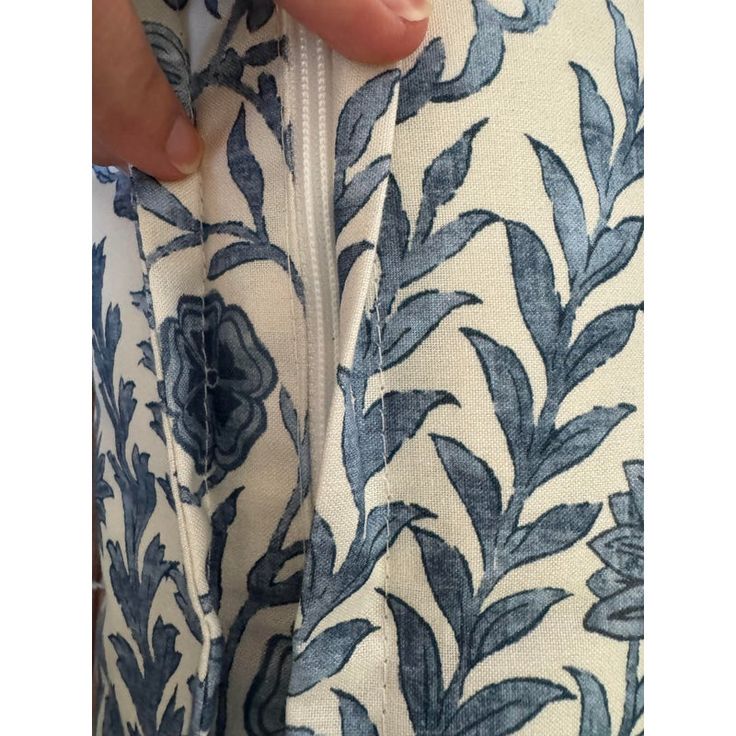 a person is holding onto the side of a blue and white floral print jacket with zippers