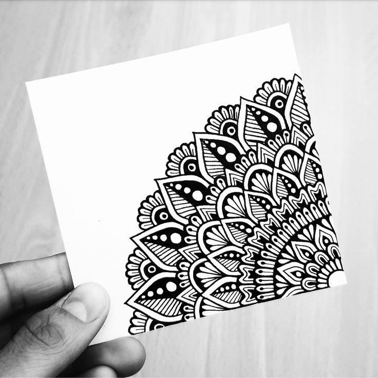 a hand holding up a piece of paper with black and white designs on it