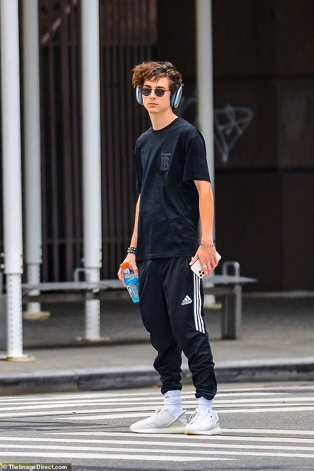 a young man wearing headphones while walking across a street