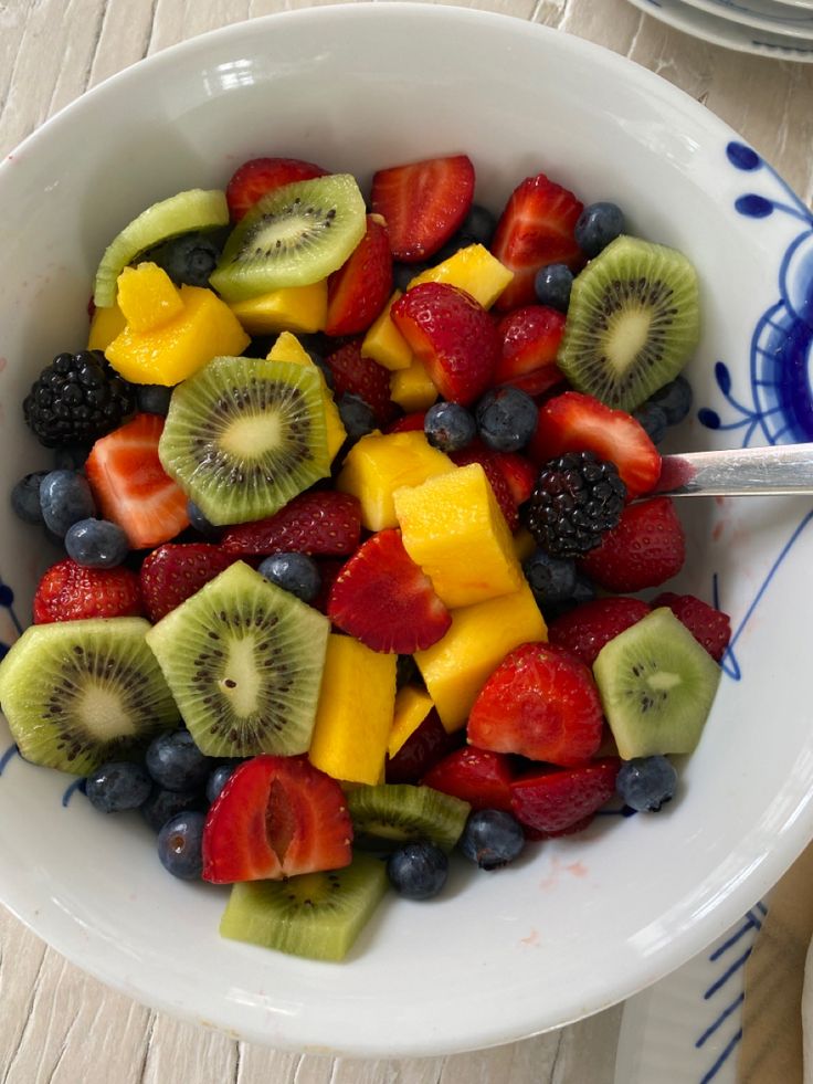 a white bowl filled with fruit on top of a wooden table