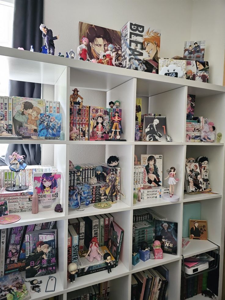 a white book shelf filled with books and anime figurines