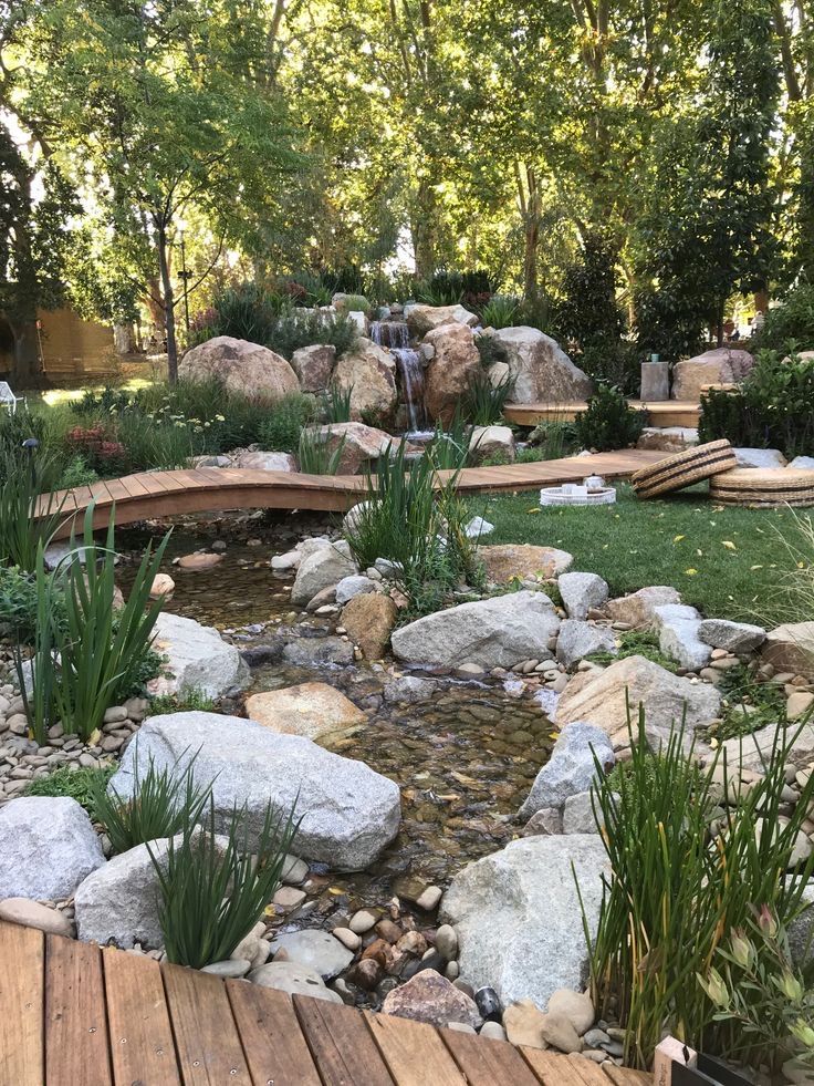 a wooden bridge over a small creek surrounded by rocks