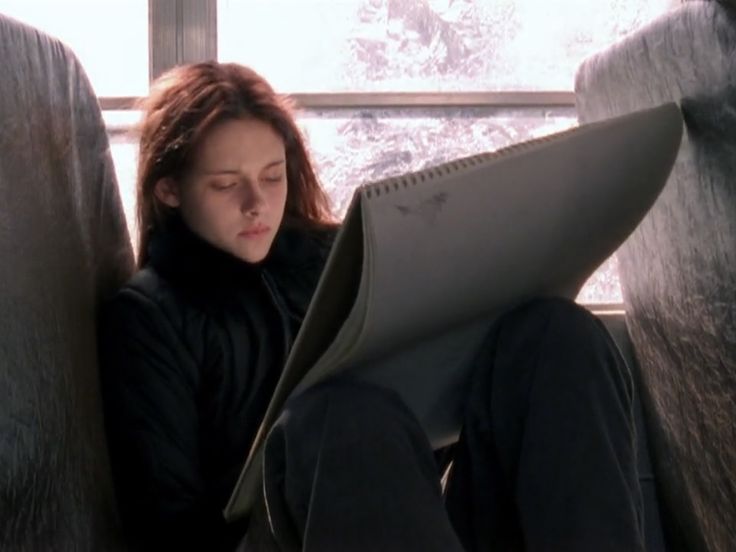 a woman sitting on a bus reading a book with her head resting on the seat