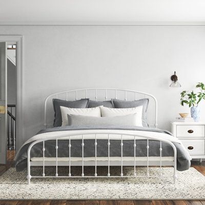 a white bed sitting in a bedroom on top of a hard wood floor