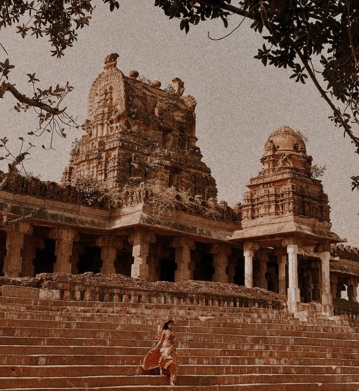 a woman is walking up some steps in front of a building that has many pillars