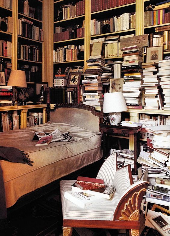 a bed sitting in front of a book shelf filled with books