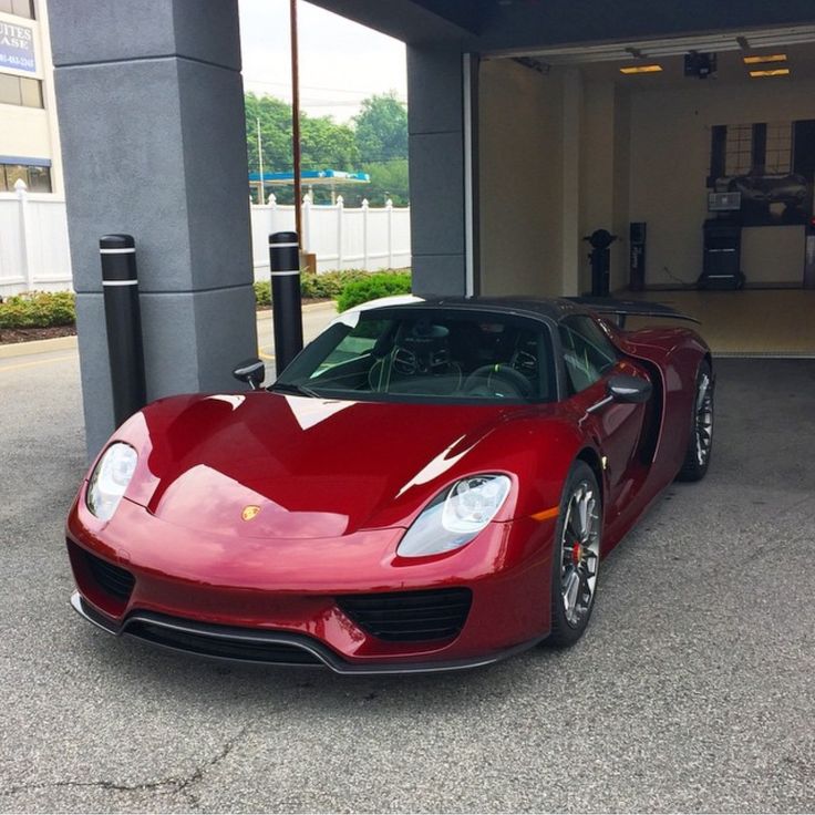 a red sports car is parked in front of a parking garage with its doors open