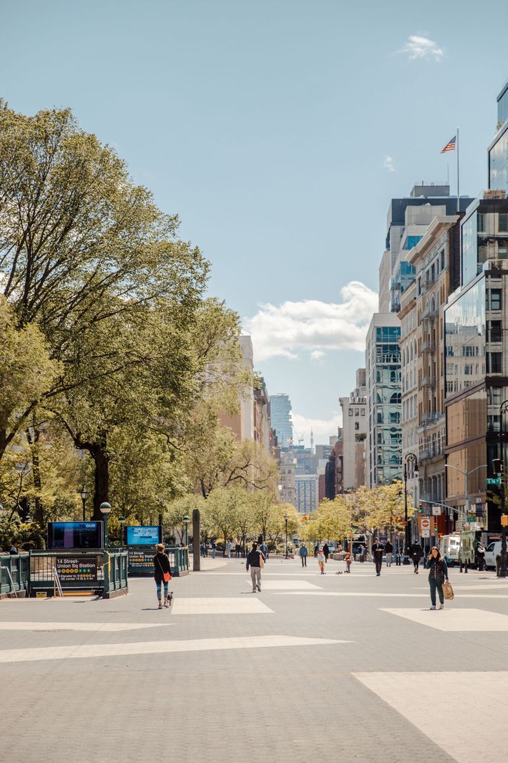 people are walking around in the middle of a large city street with tall buildings on both sides