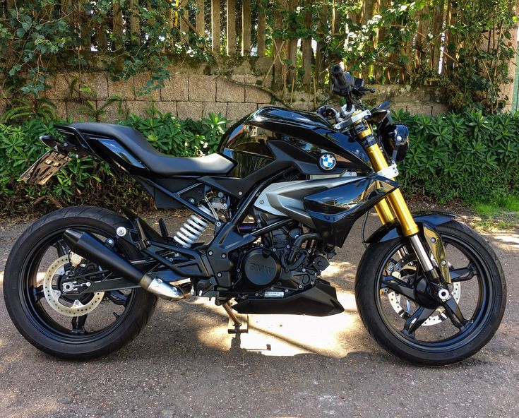 a black motorcycle is parked on the side of the road in front of some bushes