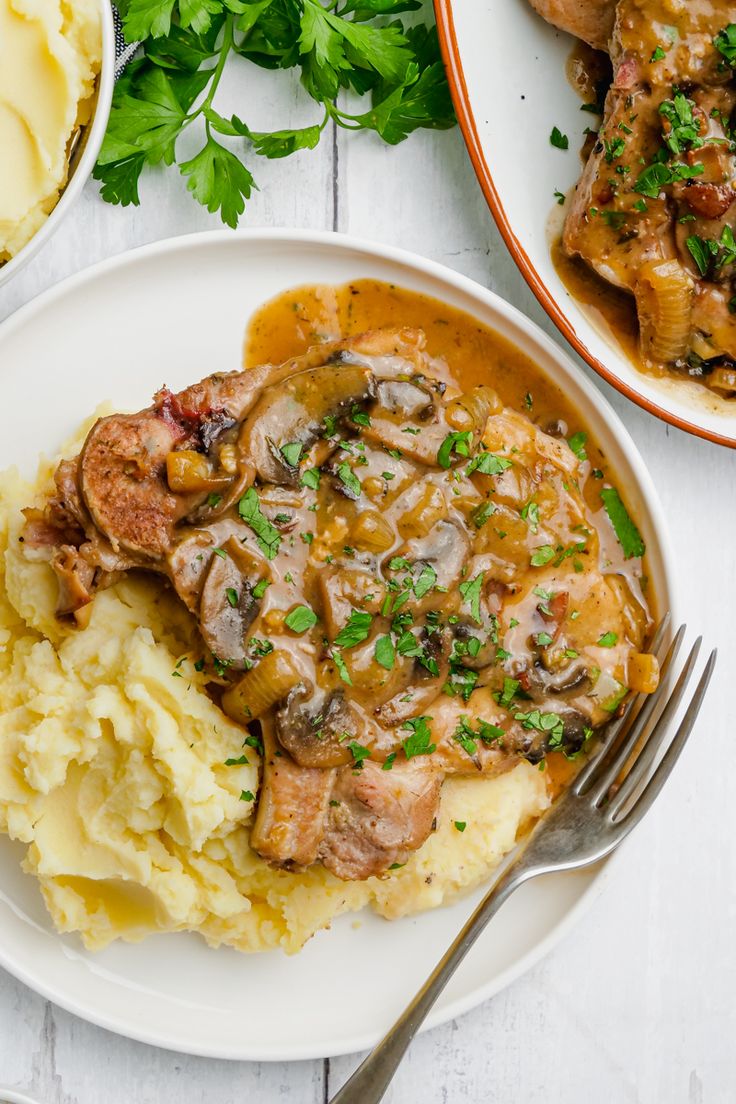 a white plate topped with mashed potatoes covered in mushroom gravy and meat