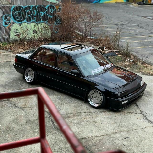 a black car parked in front of a graffiti covered wall