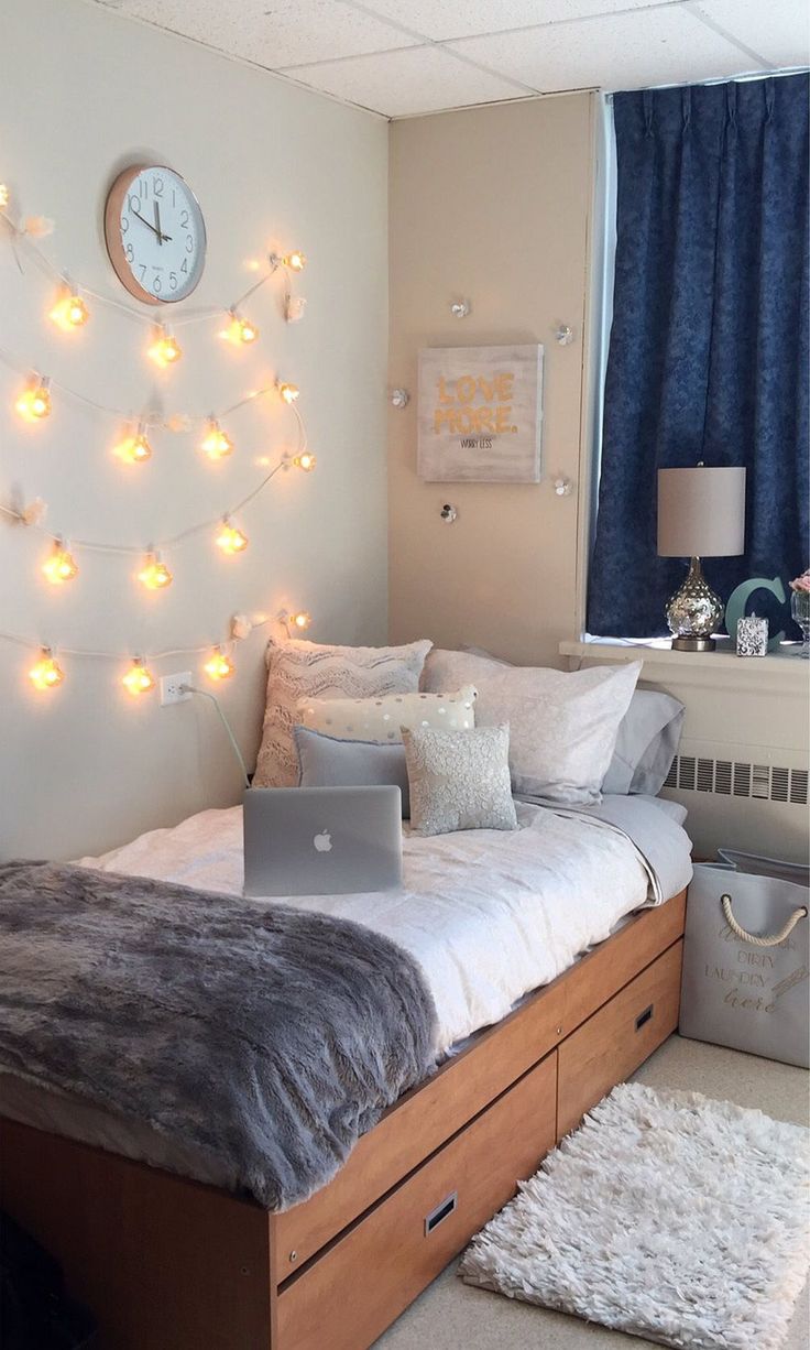 a bedroom with a laptop on the bed and lights strung from the wall behind it