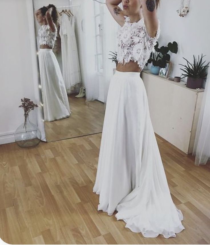 a woman standing in front of a mirror wearing a white skirt and cropped top