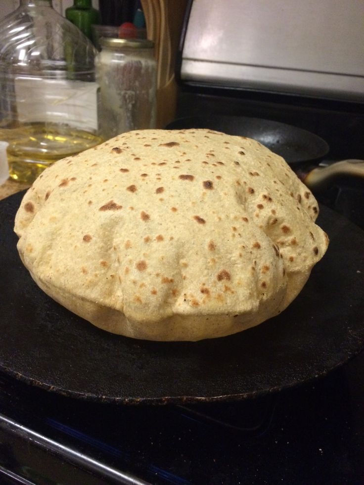 an uncooked tortilla sitting on top of a black plate next to a stove