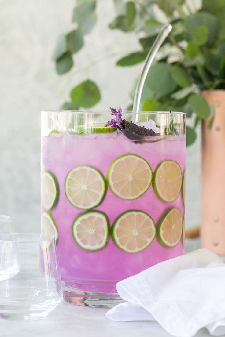 a pink drink with limes and lavender on the rim