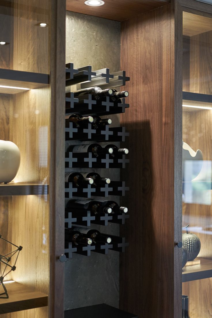 a wine rack in the corner of a room with glass doors and shelves filled with bottles