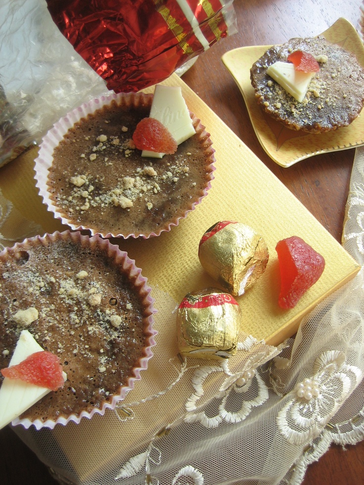 three desserts are sitting on a table next to a cupcake and some candy