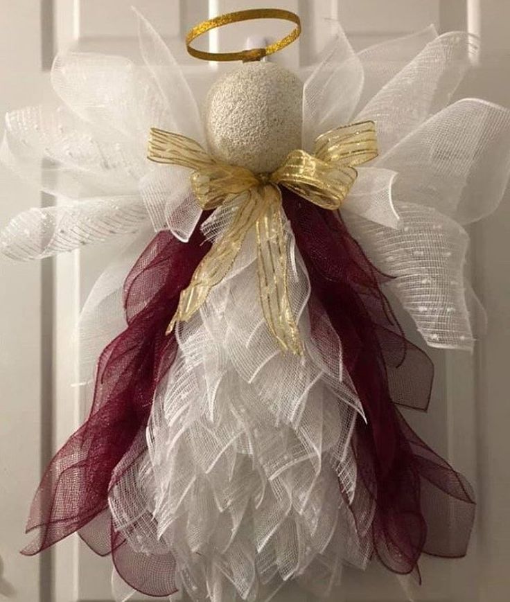 an angel ornament hanging on a door with red and white tulle attached to it