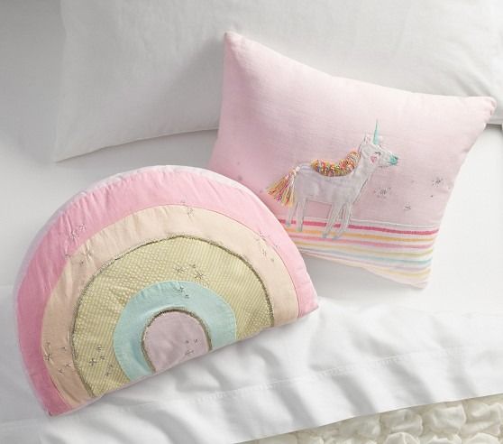 two pillows on top of a bed with white sheets and pillow cases in the shape of unicorns