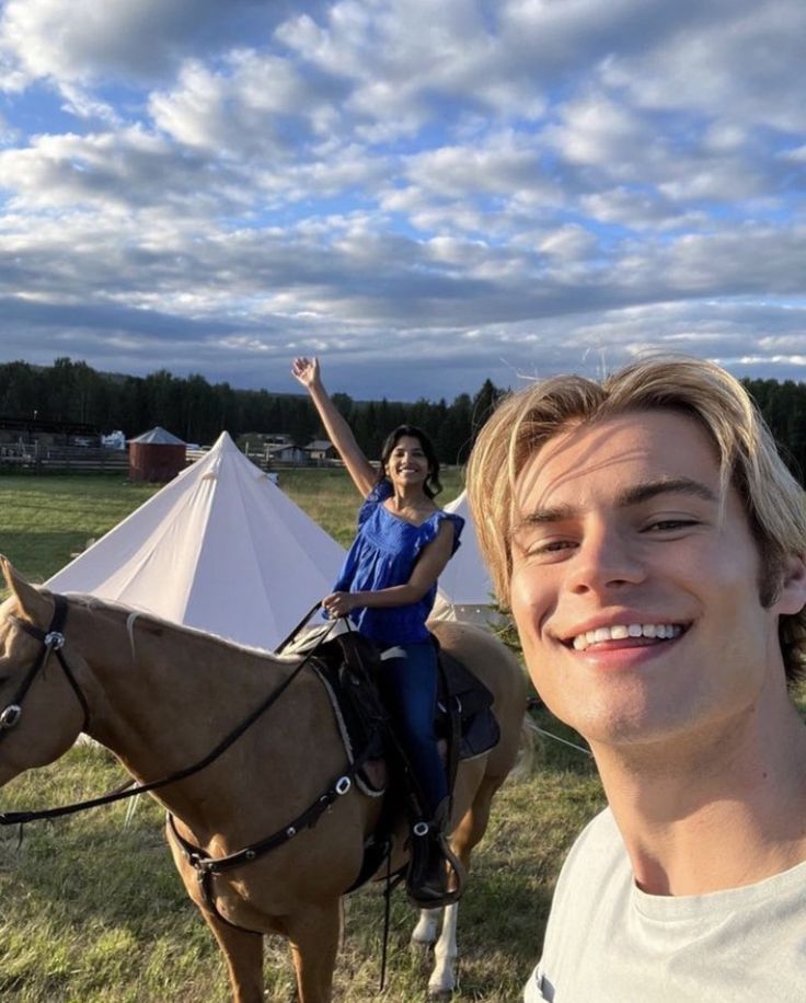 a man riding on the back of a brown horse next to a woman in a white shirt