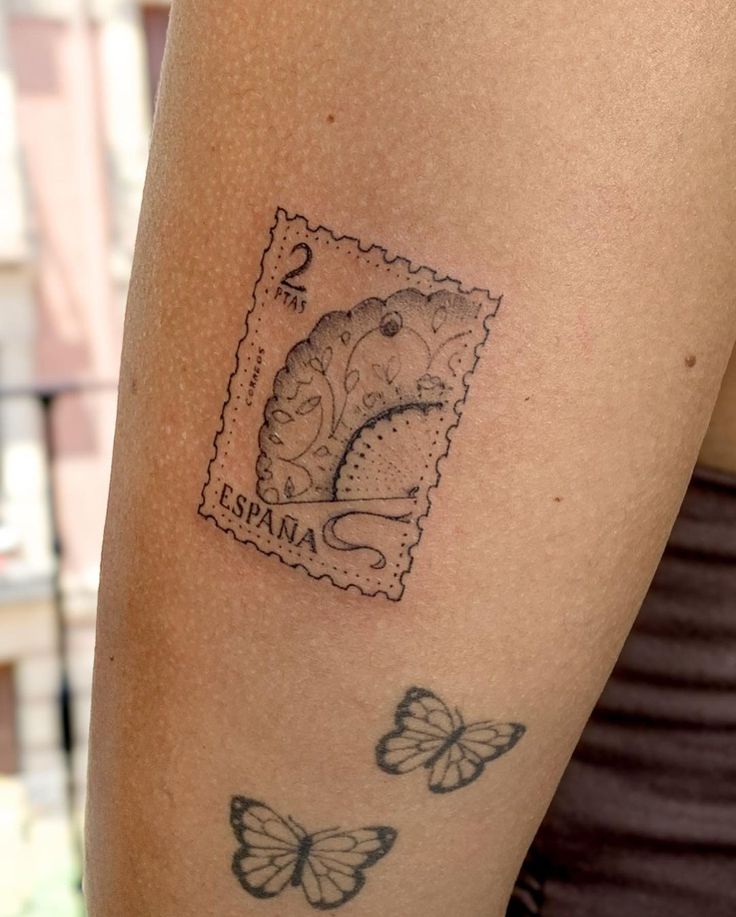 a woman's arm with a stamp on it and butterflies around the tattoo area