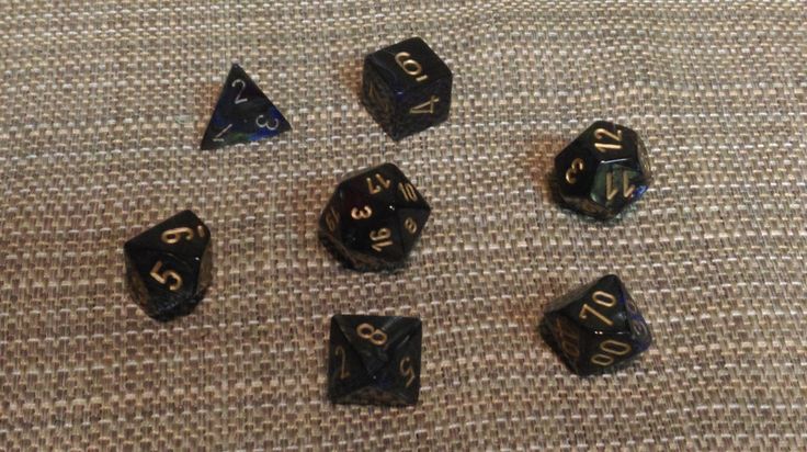 six black and gold dice sitting on top of a brown cloth covered floor next to each other