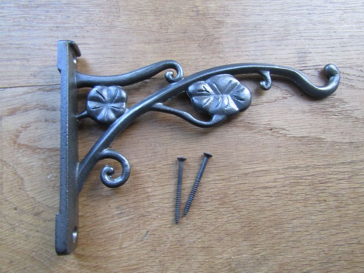 an iron handle with flowers and screws on a wooden table next to some nails